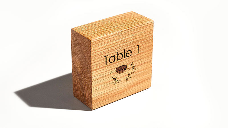 Wooden block engraved 'table 1' with a pig illustration