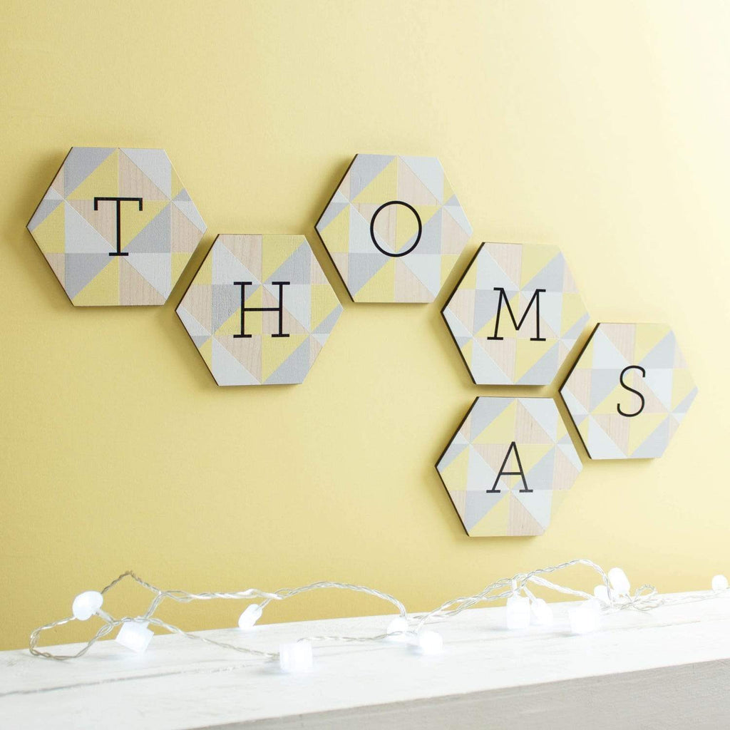Wooden tiles printed 'Thomas', hanging on a yellow wall