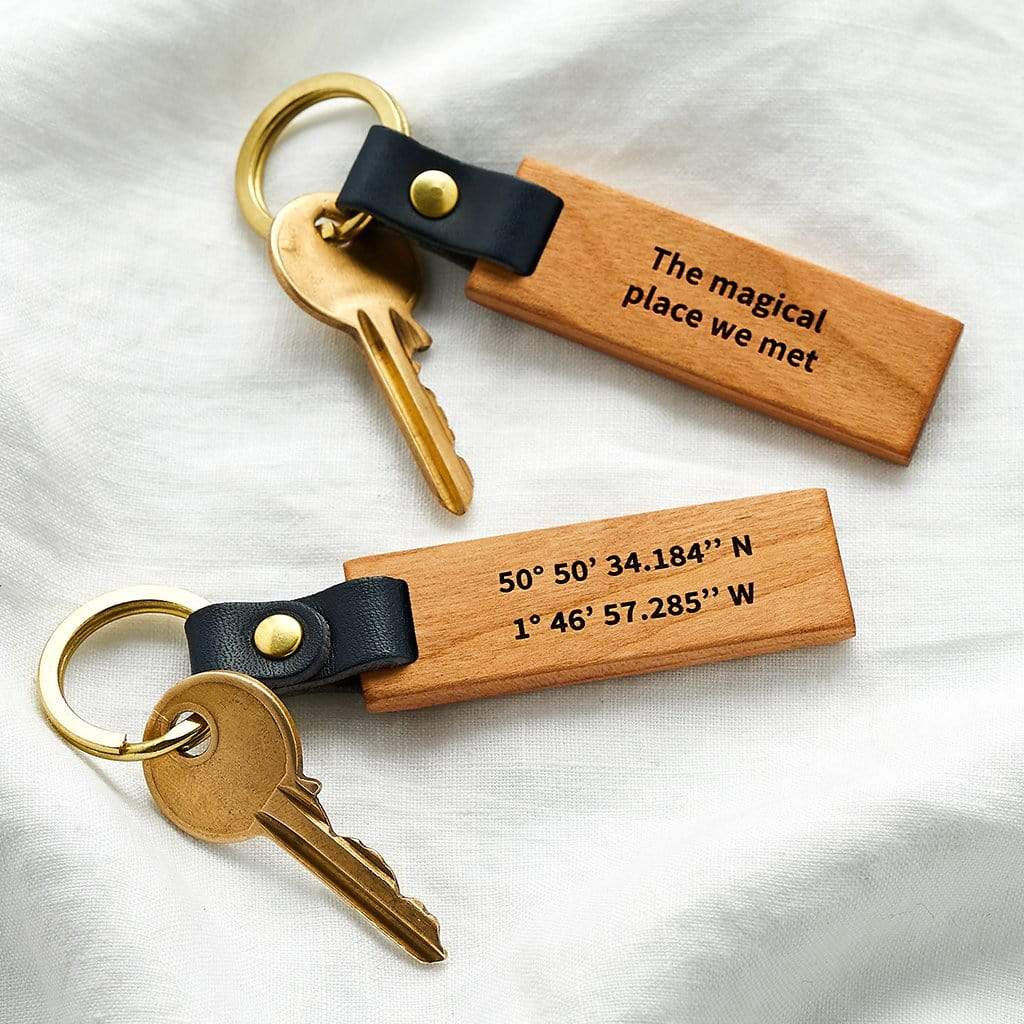Wooden keyrings engraved with coordinates and the message 'the magical place we met'