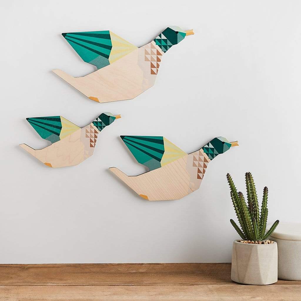 Set of three wooden duck ornaments hanging on wall