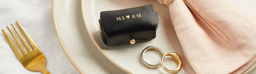 Black leather ring pouch shown with wedding rings