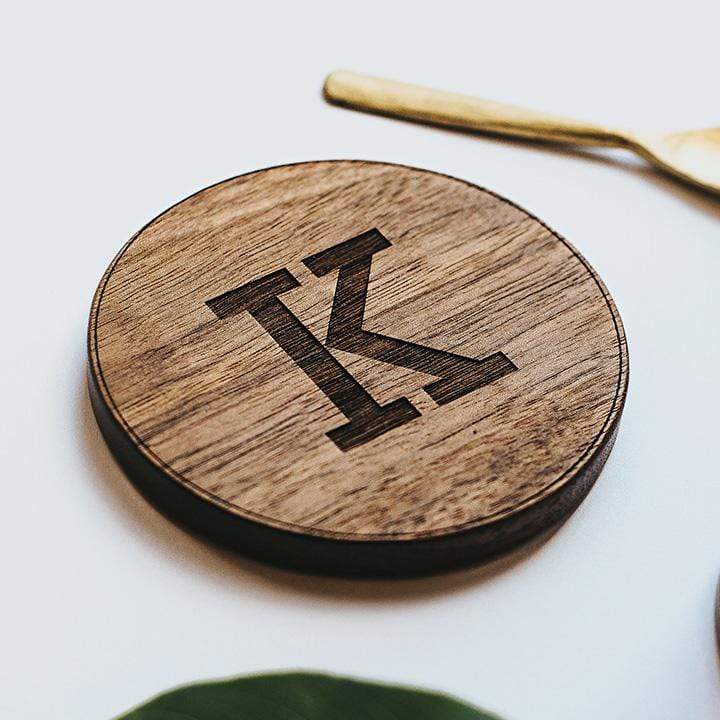 Round wooden coaster engraved with letter 'K'