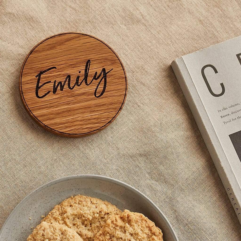 Wooden coaster engraved 'Emily', shown on a coffee table