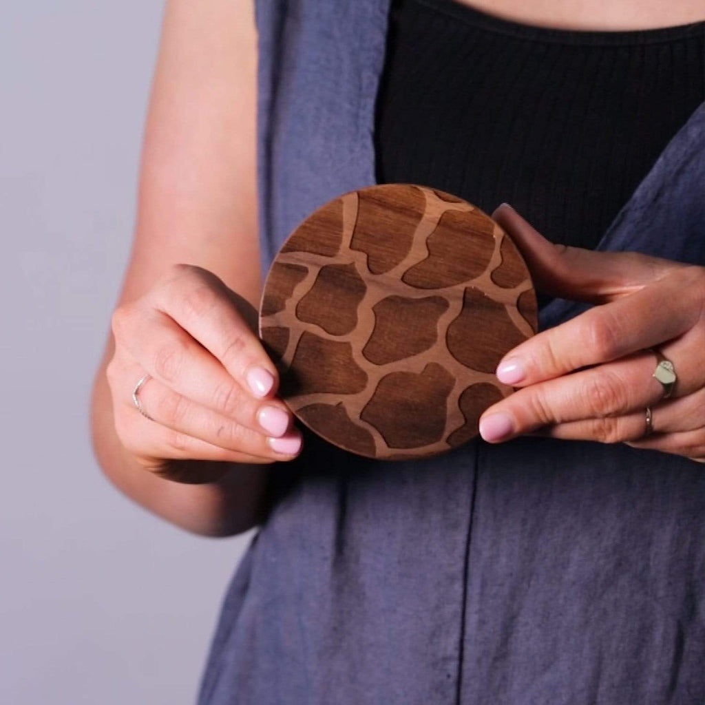 Female hand model holding wooden giraffe print coaster